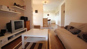 A living room with a sofa, a coffee table, a TV, and shelves with various items. - Apartment in Fazana With Garden & Terrace (Fazana)