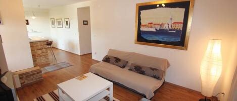 A living room with a sofa, a coffee table, a lamp, and a painting on the wall.