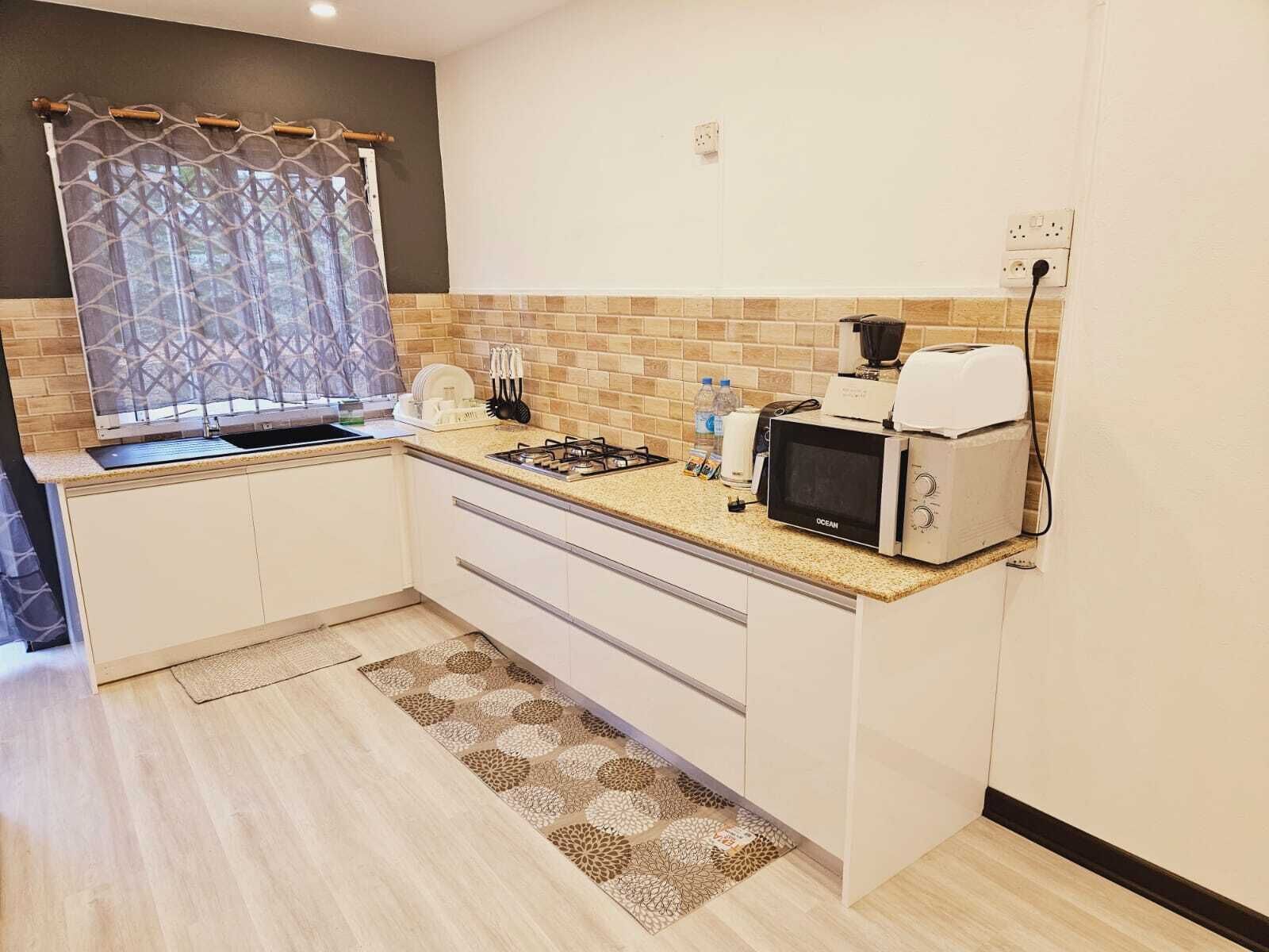 Una cucina compatta con piano cottura a gas, forno a microonde e tostapane.