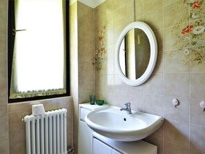 A bathroom with a white sink, a round mirror, and a radiator. - Belvilla by OYO Del03/1 (Germignaga)