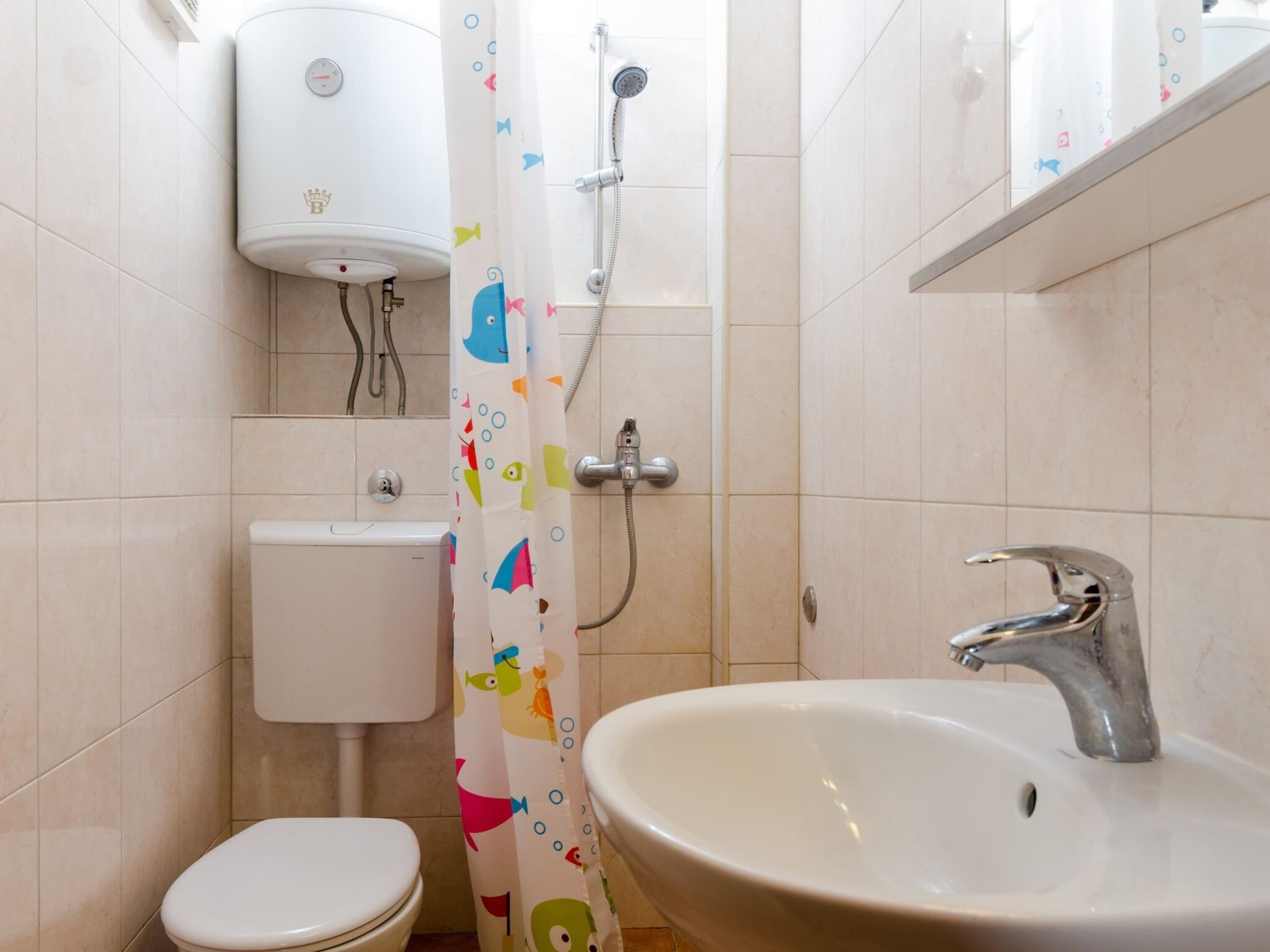 Une salle de bain avec des toilettes, un lavabo et une douche.