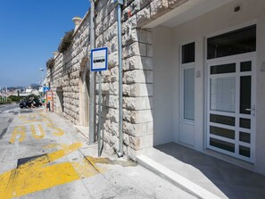A stone building with a bus stop sign, a white door, and a clear sky.