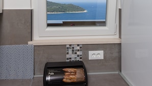 Una cocina con ventana que ofrece vistas al mar, un tostador y un salpicadero decorativo.