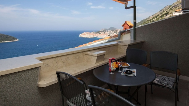 Un balcón con mesa y sillas que da a la vista del mar.