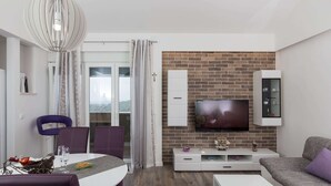 Una sala de estar moderna con televisor, armarios blancos y pared de ladrillo.