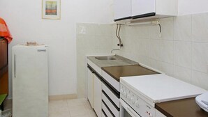 Una cocina pequeña equipada con refrigerador, estufa, pileta y alacenas.