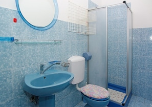 Ein Badezimmer mit blauem Waschbecken, WC und Dusche.