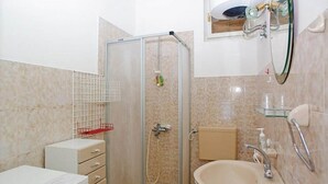 Un baño con ducha de vidrio, lavabo con espejo e inodoro.