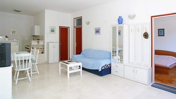 Una habitación con cama, sofá, mesa de comedor con sillas, televisor y armario.