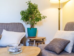A cozy living room with a round wooden coffee table, a teal potted plant, and a floor lamp. - Apartments Lion - Sea House 1 (Dubrovnik)