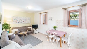 A living room with a sofa, a small table, a TV, and a dining area with chairs and a table. - Apartments Lion - Sea House 1 (Dubrovnik)