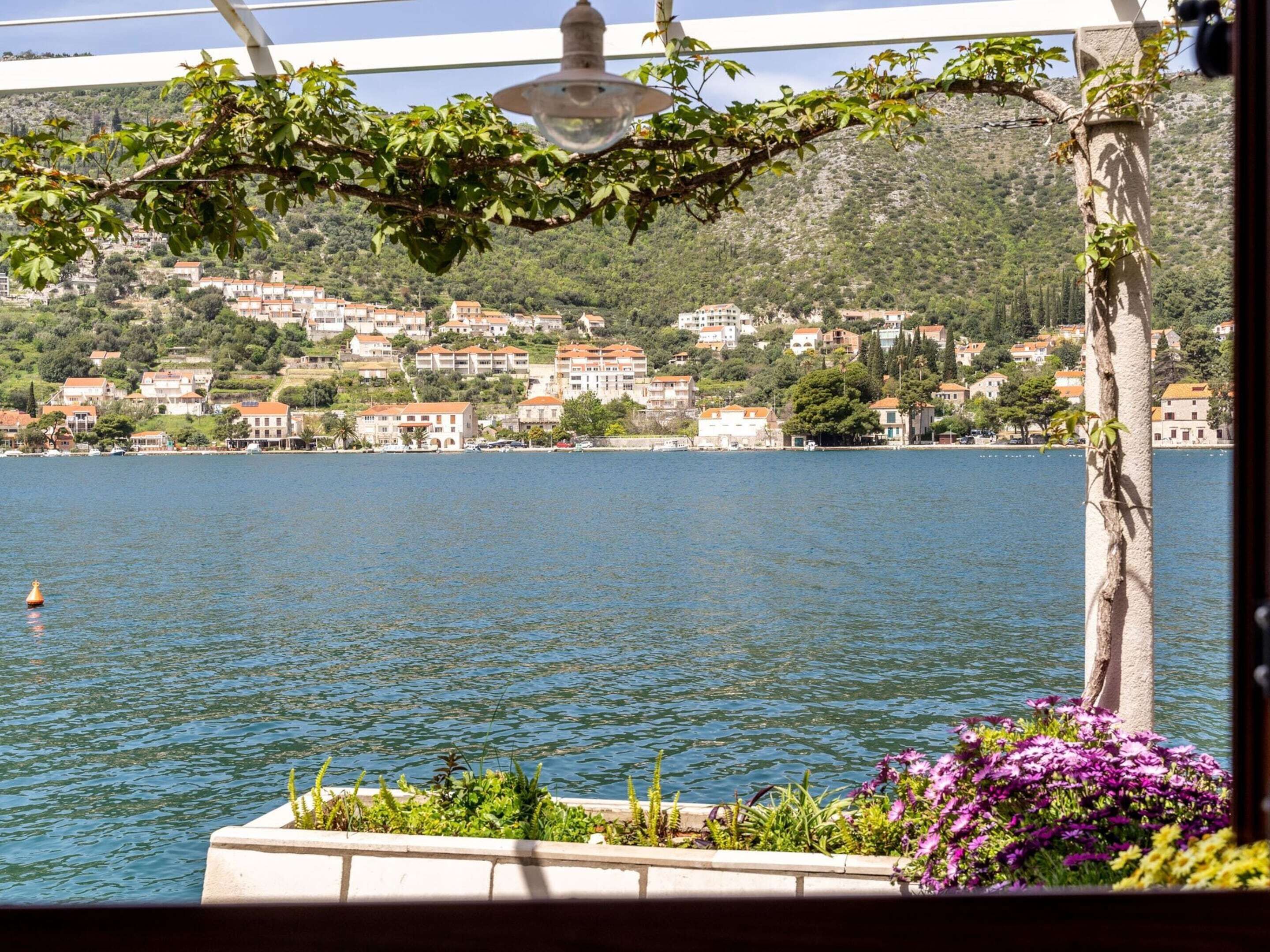 A coastal town with houses on a hillside, a body of water, and a lamp post.