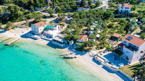 An aerial view of a coastal village with houses, a beach, and clear turquoise waters. - Apartments Kola's Mill - Comfort One Bedroom Apartment With Terrace and Sea View (Dubrovacko Primorje)