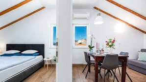 Een moderne, goed verlichte kamer met een bed, een eettafel met stoelen en een bank.