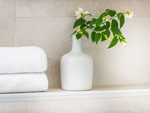 A bathroom with a white towel stack and a white vase with a plant. - Apartments Terra - One Bedroom Apartment With Balcony and Garden View (Dubrovnik)