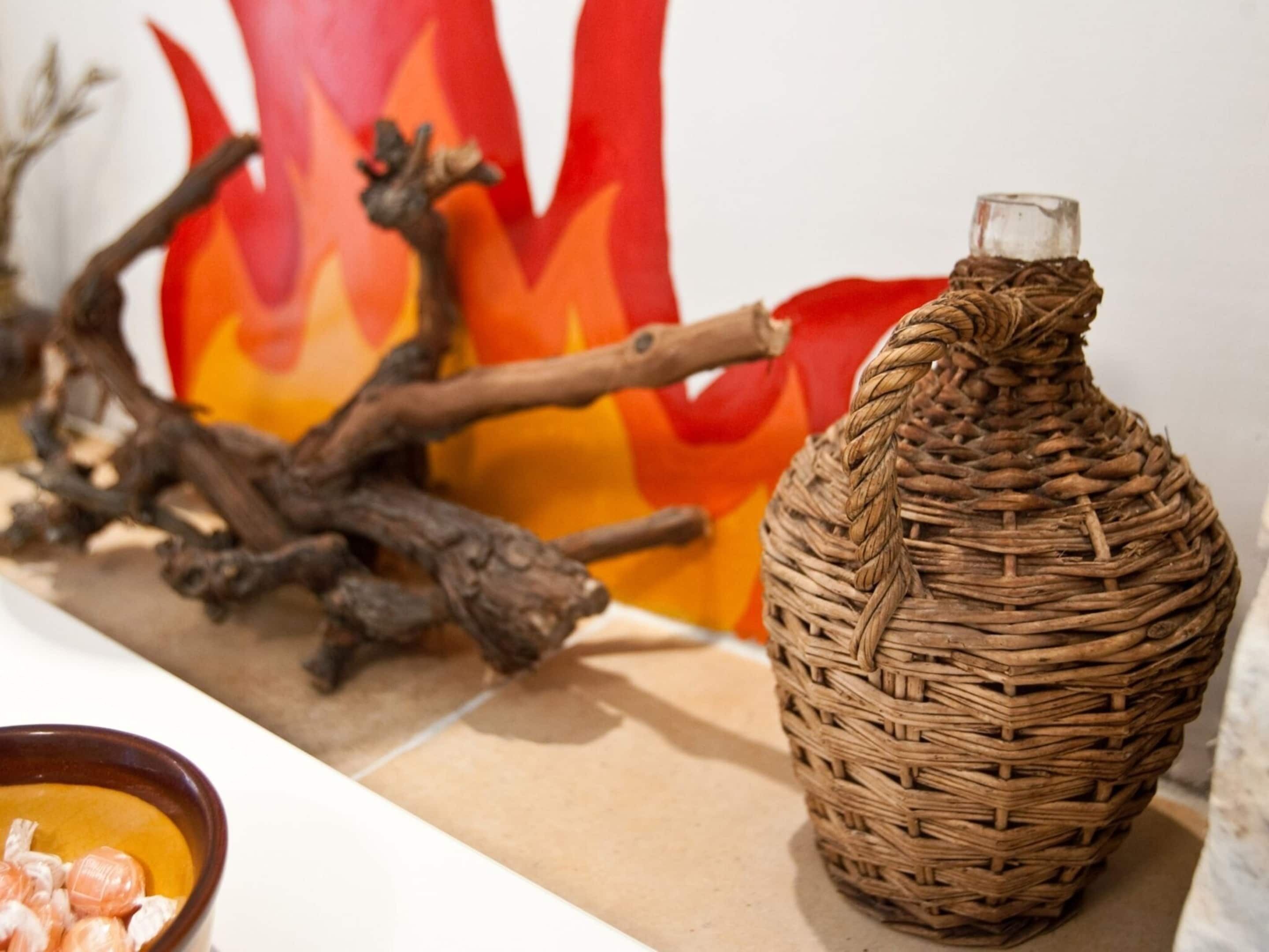 A wicker vase with a glass top on a shelf.