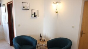 A room with two teal armchairs, a small round table with a bottle and glasses, and wall-mounted light fixtures. - Apartments Baldo - Two Bedroom Apartment With Sea View (Dubrovacko Primorje)