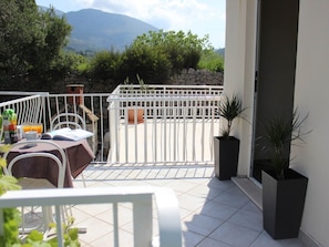 A balcony with a table set for breakfast, a white railing, and potted plants. - Apartments Baldo - Two Bedroom Apartment With Sea View (Dubrovacko Primorje)