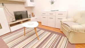 A modern living room with a flat-screen TV, a small white table, a beige sofa, and a striped rug. - Apartments Peselj-three Bedroom Apartment With Terrace and Sea View (Smokvica)