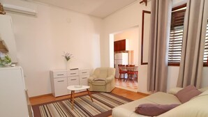 A living room with a sofa, a small table, a cabinet, and a kitchen area in the background. - Apartments Peselj-three Bedroom Apartment With Terrace and Sea View (Smokvica)