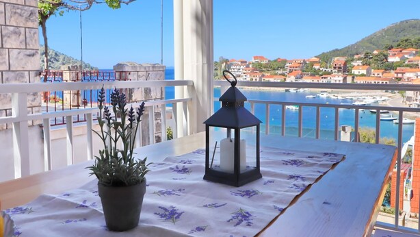 A balcony with a table, potted plant, and lantern. - Apartments Peselj-three Bedroom Apartment With Terrace and Sea View (Smokvica)