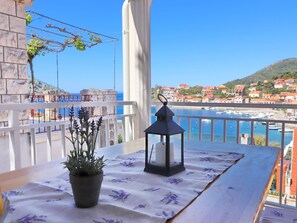 A balcony with a table, potted plant, and lantern. - Apartments Peselj-three Bedroom Apartment With Terrace and Sea View (Smokvica)