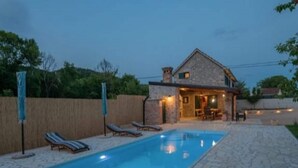 Una piscina con lettini da sole e un patio in pietra.