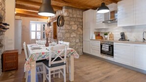 Una cucina accogliente con travi in legno, mobili bianchi e un'area pranzo con tavolo imbandito per quattro persone.