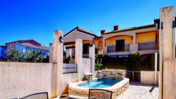 Une terrasse avec une table, des chaises et une petite piscine.