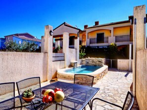 Eine Terrasse mit Tisch, Stühlen und einem kleinen Pool.
