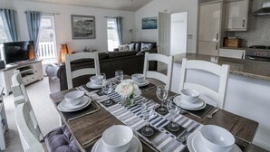 A dining area with a table set for four, a sofa, and a television in the background. - Seacroft (Narberth)