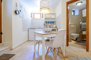 A compact kitchen with a dining table, chairs, and a hanging light fixture. - Apartment Sympa - Studio Apartment A2 (Dubrovnik)
