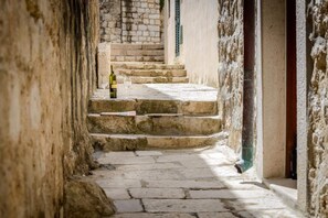 A stone staircase leading up to a door, with a bottle and glass on the steps. - Apartment Sympa - Studio Apartment A2 (Dubrovnik)