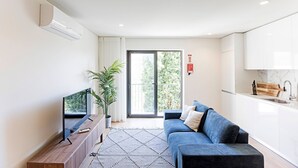 Un salón moderno con sofá, televisor y un ventanal con vistas a zonas verdes.