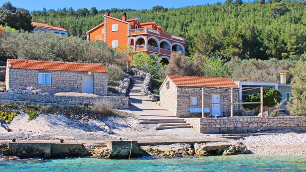 A coastal property with stone buildings, a clear blue sea, and a forested hill in the background. - Apartments Sea Line - Two Bedroom Apartment With Terrace and Sea View (Blato)