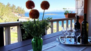 A balcony with a table set for two, a green vase with flowers, and a view of the sea. - Apartments Sea Line - Two Bedroom Apartment With Terrace and Sea View (Blato)