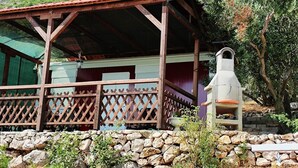 Une construction rustique en bois, dotée d’un porche abrité, de murs en pierre et d’une cheminée.