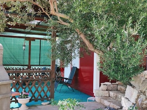 A covered outdoor seating area with a wooden pergola, a red wall, and a stone staircase. - Apartments Dalamar - Mobile Home With Patio (Mljet)