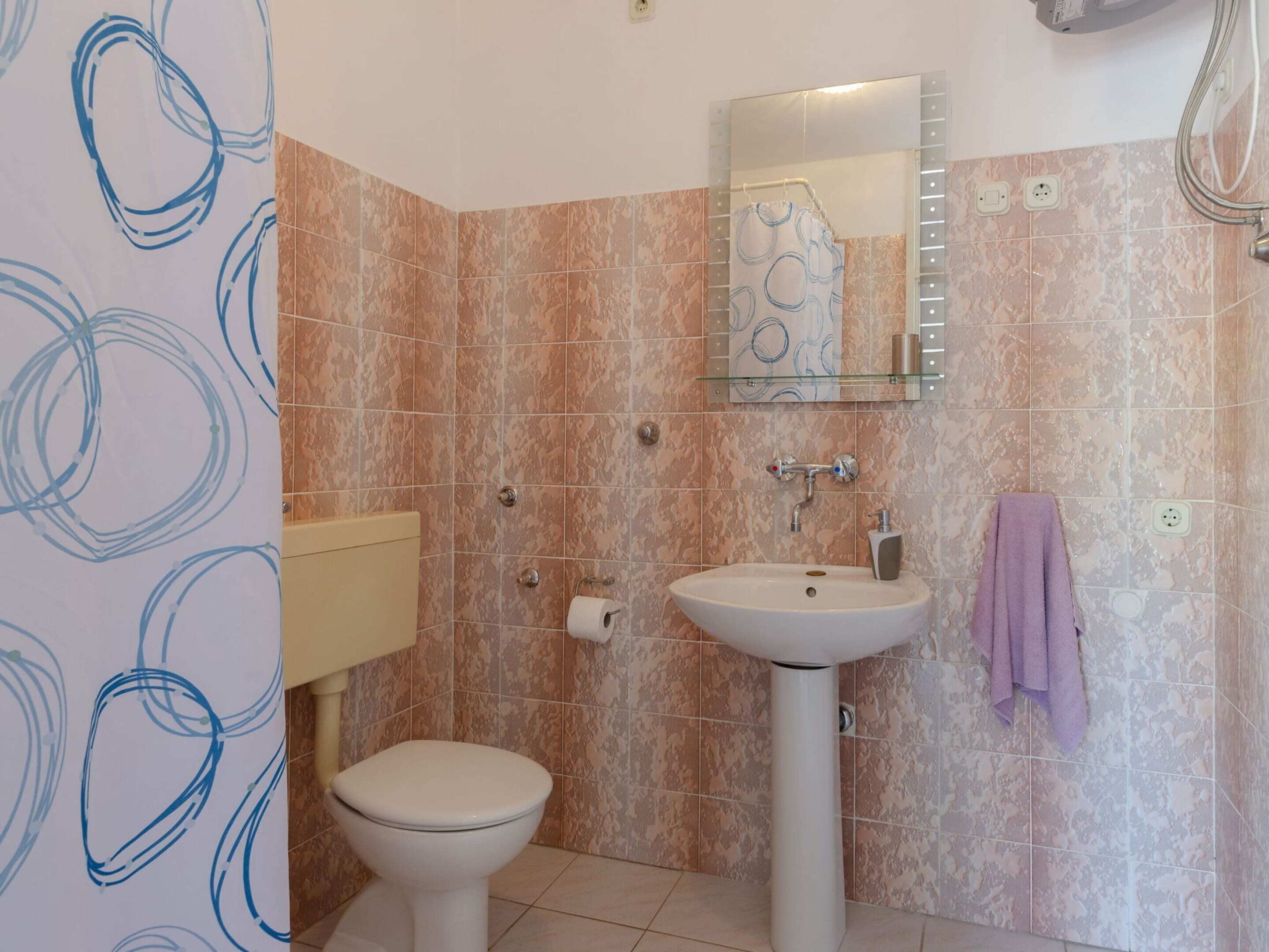 Een badkamer met toilet, wastafel en douche.