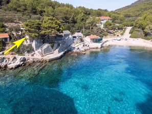 A coastal area with clear blue waters, stone buildings, and a beach. - Seafront Apartments Olivera-standard One Bedroom Apartment With Balcony and Sea View (Blato)