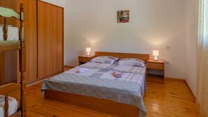 A bedroom with a wooden bed, two bedside tables with lamps, a wooden wardrobe, and a small painting on the wall. - Seafront Apartments Olivera-standard One Bedroom Apartment With Balcony and Sea View (Blato)