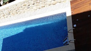 Ein Swimmingpool mit glatter, blauer Wasseroberfläche, umgeben von einer Steinsäule und einem Holenzaun.