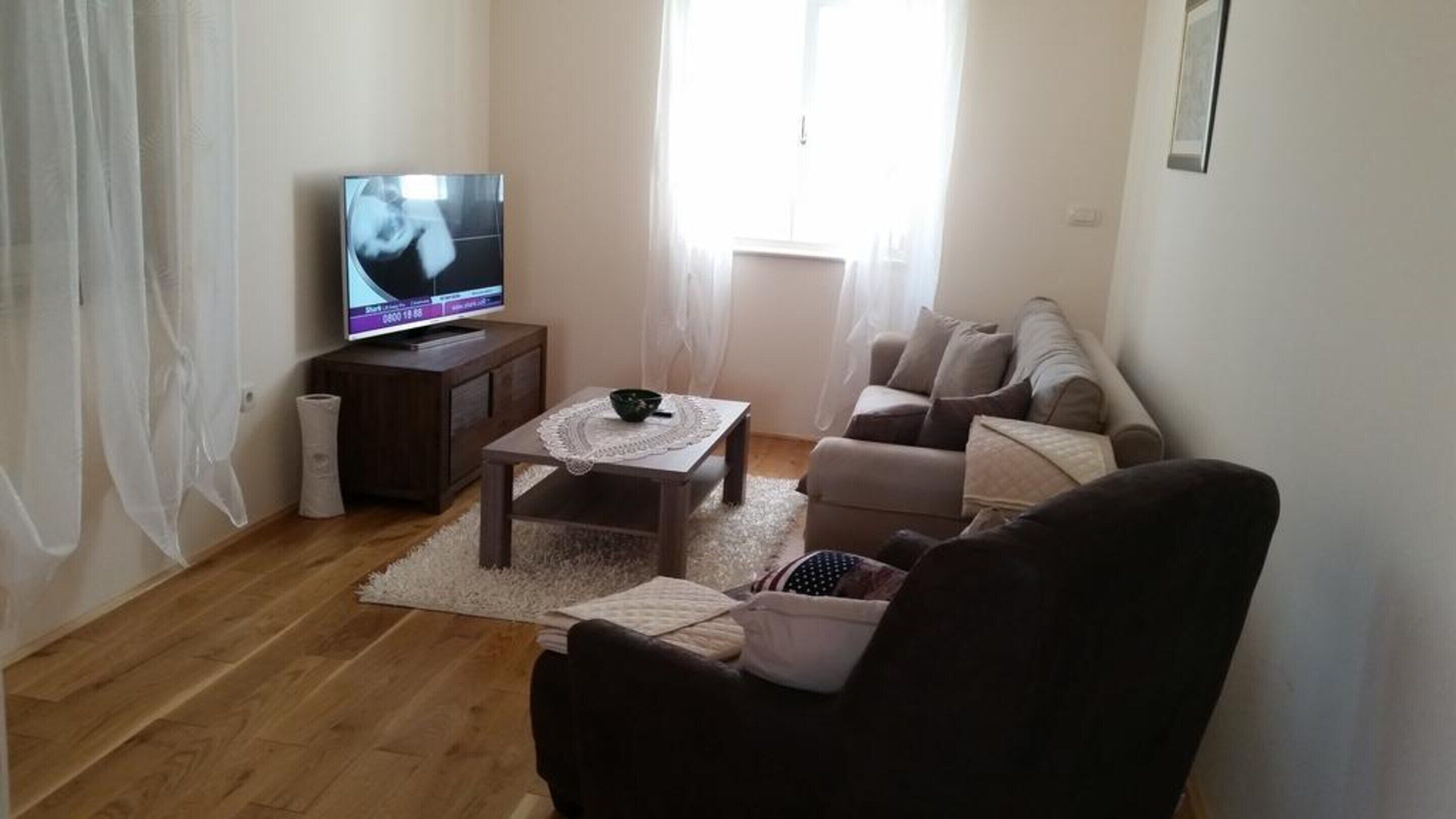 A living room with a television, a sofa, a coffee table, and a chair.