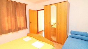 A bedroom with two beds, a wardrobe, and a door leading to another room.