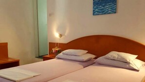 A double bed with two pillows and a nightstand with a vase of flowers.
