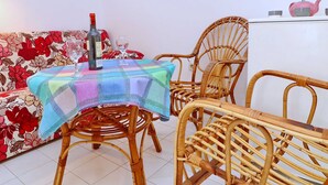 A room with a dining table covered by a colorful tablecloth, surrounded by wicker chairs. - Apartments More & Ja - Superior One Bedroom Apartment With Terrace and Sea View (Ston)