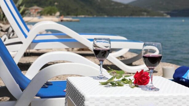 A beachside setting with lounge chairs and a table with two glasses of red wine and a red rose. - Apartments More & Ja - Superior One Bedroom Apartment With Terrace and Sea View (Ston)