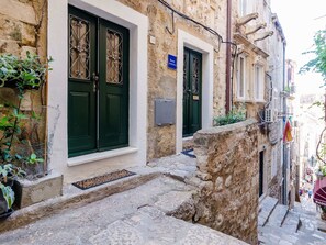 A narrow stone building with green doors and a small window. - Apartment Little Star II - Two-bedroom Apartment With City View (Dubrovnik)