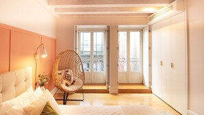 Een slaapkamer met een bed, een hangstoel en uitzicht op het balkon.