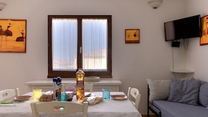 Un comedor con una mesa dispuesta para dos, un sofá y obras de arte en las paredes.